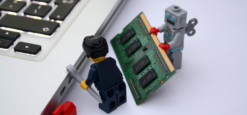 Robot lego helping lego man fix computer