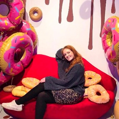 Emma Brooks, a BU student, on placement at an event sat at a set surrounded by large novelty doughnut decorations