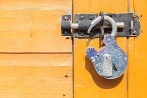 Unlocked padlock securing a latch on a yellow door