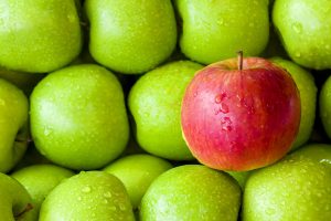 A red apple with green apples in the background