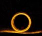 Burning steel wool being swirled in a circle at night to form a zero with slow exposure