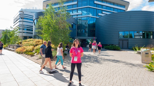 A student ambassador outside the Fusion Building on Talbot Campus, with guests and other ambassadors in the background